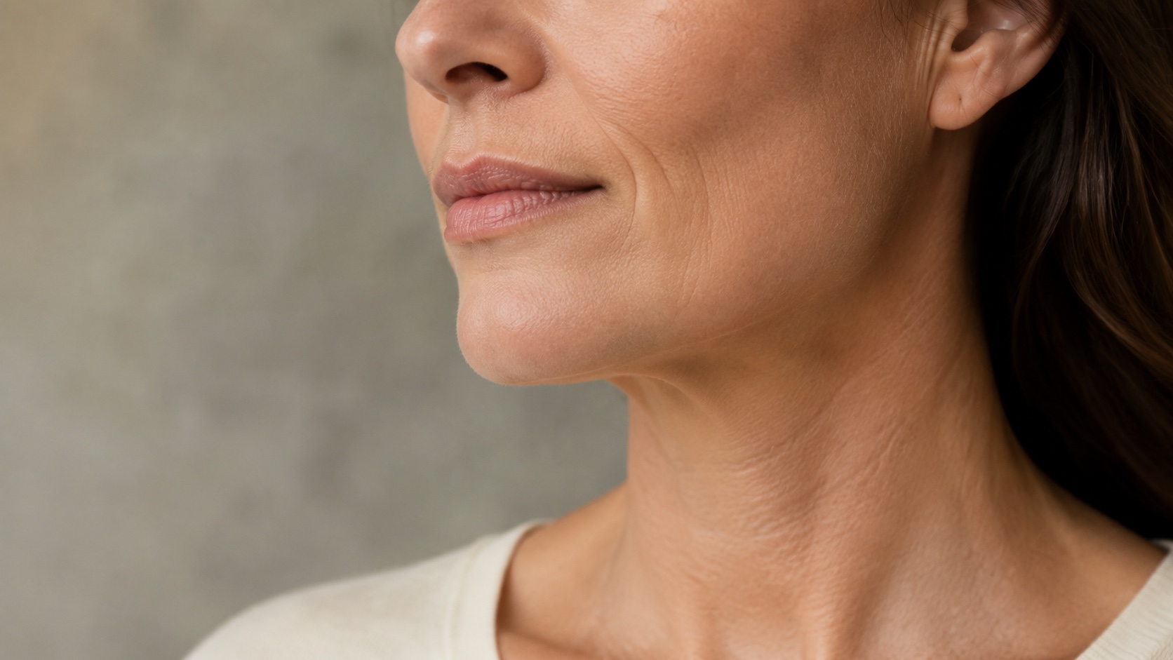 Close side view of a woman's cheek, jaw and neck in soft natural light
