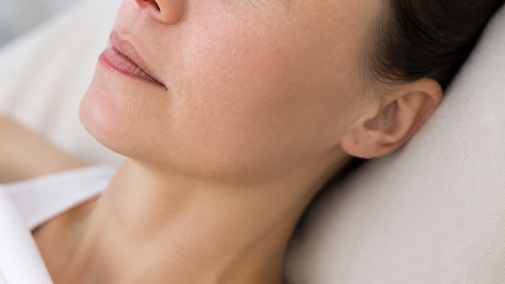 Illustrative close-up of a reclining woman with her cheek and jaw visible in soft daylight